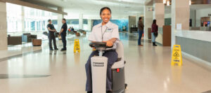 ccs employee sitting on top of an industrial mopper
