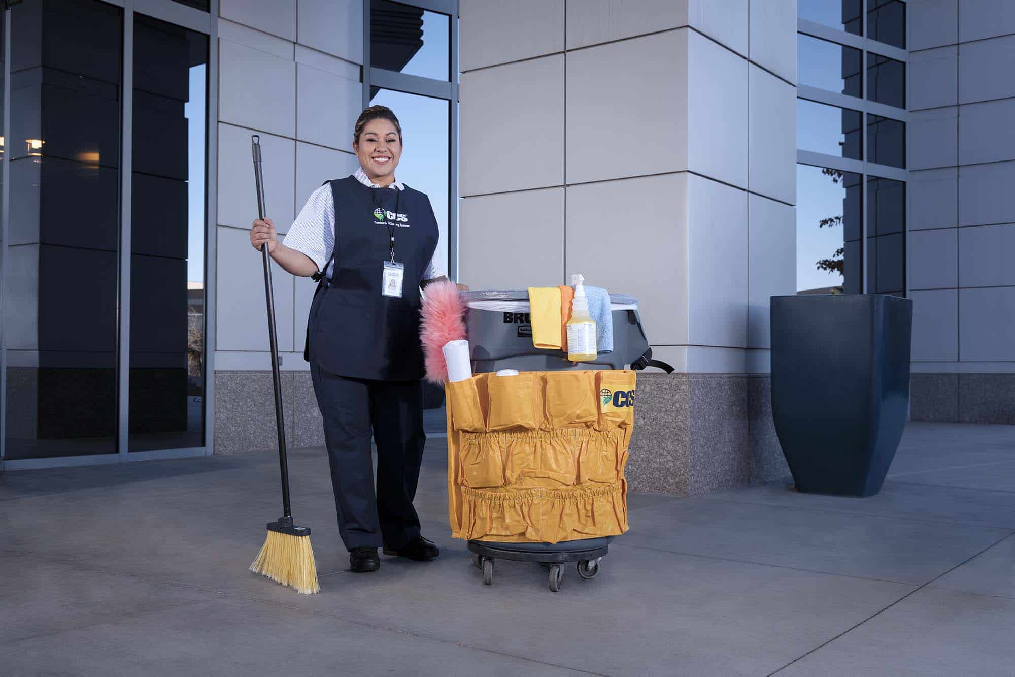 CCS Female standing outside of a building with her cleaning materials