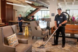 two ccs employees mopping and vacuuming the lobby of a commercial residential facility