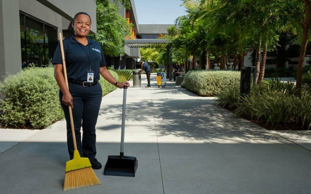 ccs woman employee sweeping the sidewalk of a building