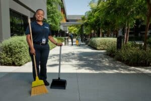 ccs woman employee sweeping the sidewalk of a building