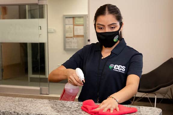 ccs employee wiping down a counter with disinfecting spray